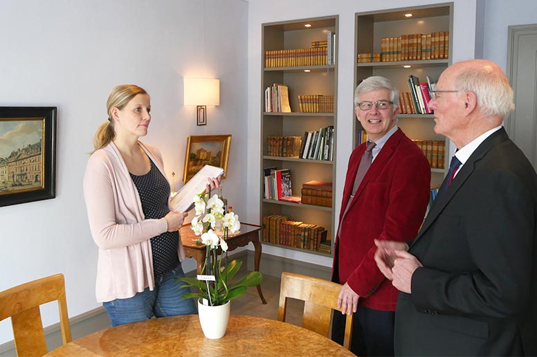 Pfarrer Gitter (m.) und Jörg Wehling (r.) übergeben im Bankhaus Metzler die Dokumentation zur erfolgreichen Sammelaktion an Britta Christopeit (l.): Über 10.000 Euro wurden gespendet